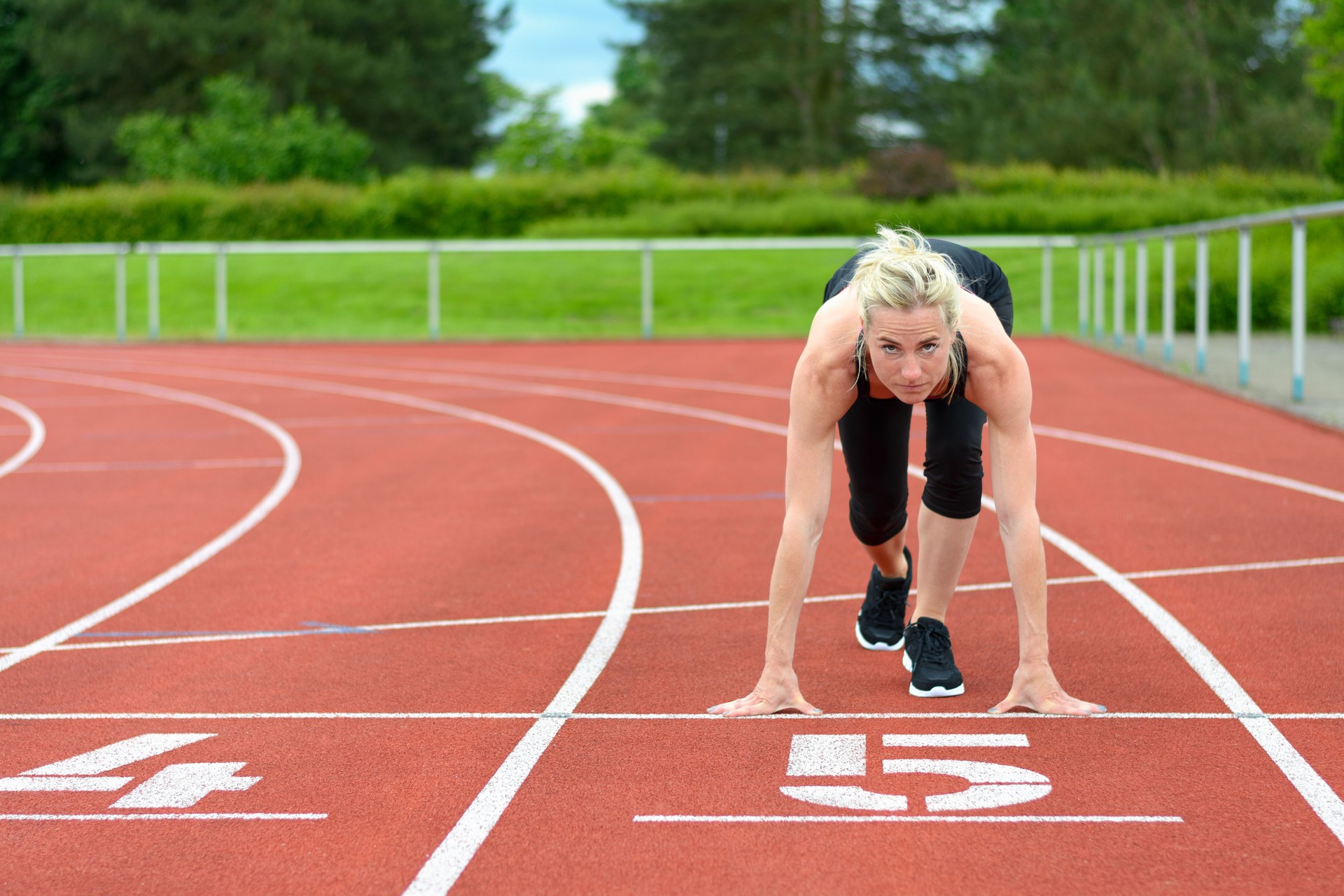 Sportliche Frau im den Starterposition auf der Strecke